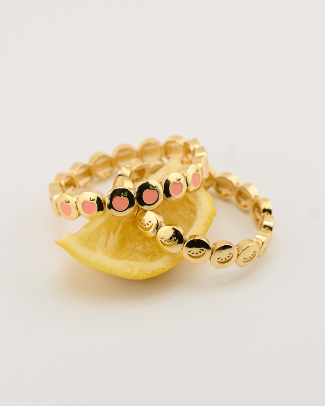 Gold rings and cocktail bracelets of peach and lemon slice design