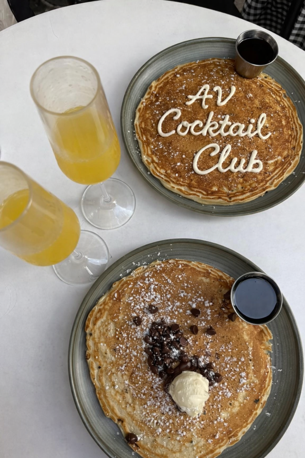 Pancakes and mimosas at brunch with icing stating AV Cocktail Club in the top left pancake for AV Jewels Jewelry.