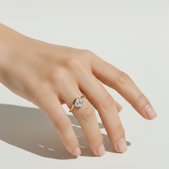 Hand wearing a gold ring with a diamond on a light background