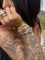 Close-up of a person with tattoos and jewelry, including bracelets and rings.