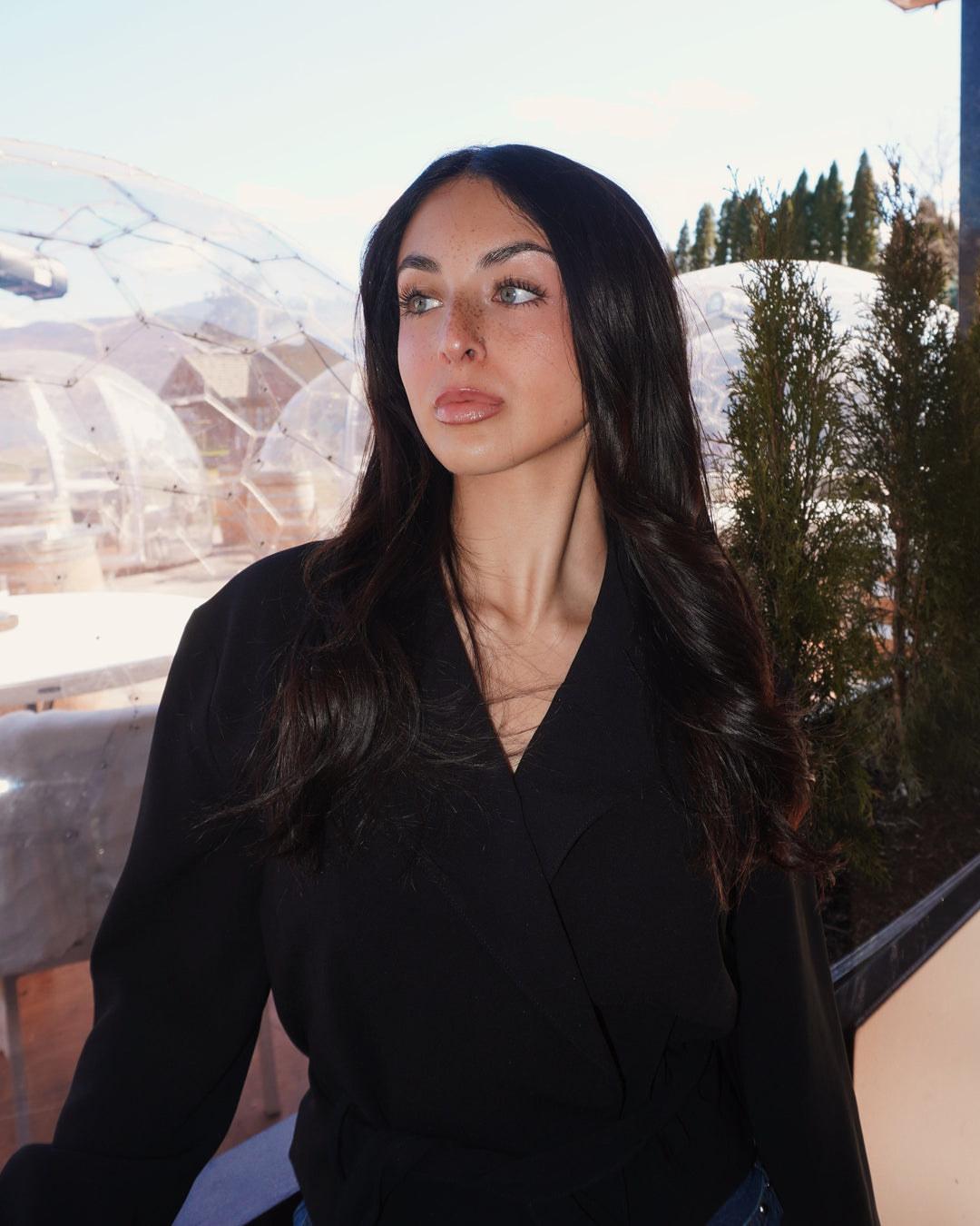 Woman in a black coat standing on a balcony with a snowy landscape in the background - modeling AV Jewels Jewelry  "AV Cocktail Club "