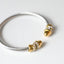 Silver and gold bracelet with cable design on a light gray background