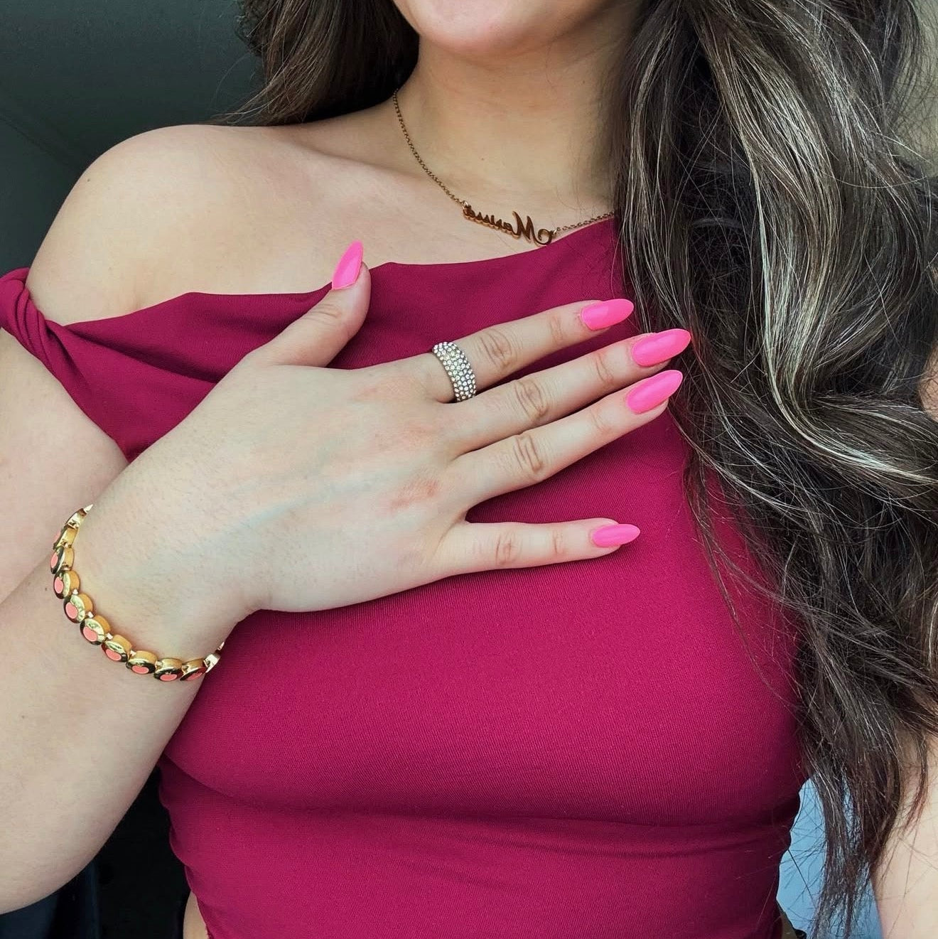 Woman wearing a pink top with a gold bracelet and ring, against a neutral background wearing the ice ave ring and Peach Bellini bracelet