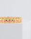 Gold bracelet with peach enamel design  on a light gray background