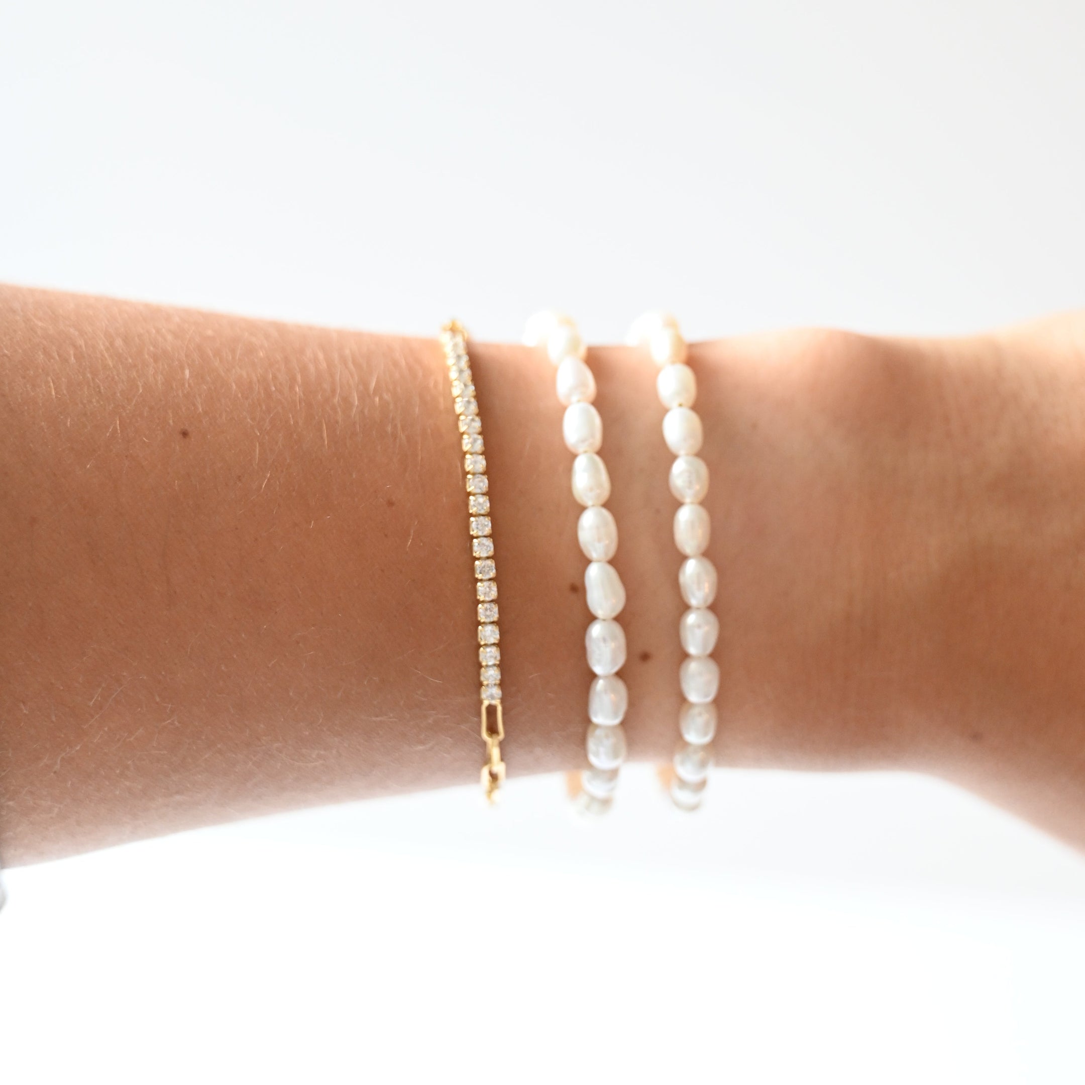 Pearl bracelets on a person's wrist against a white background