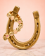 Gold horseshoe with decorative charms on a pink background